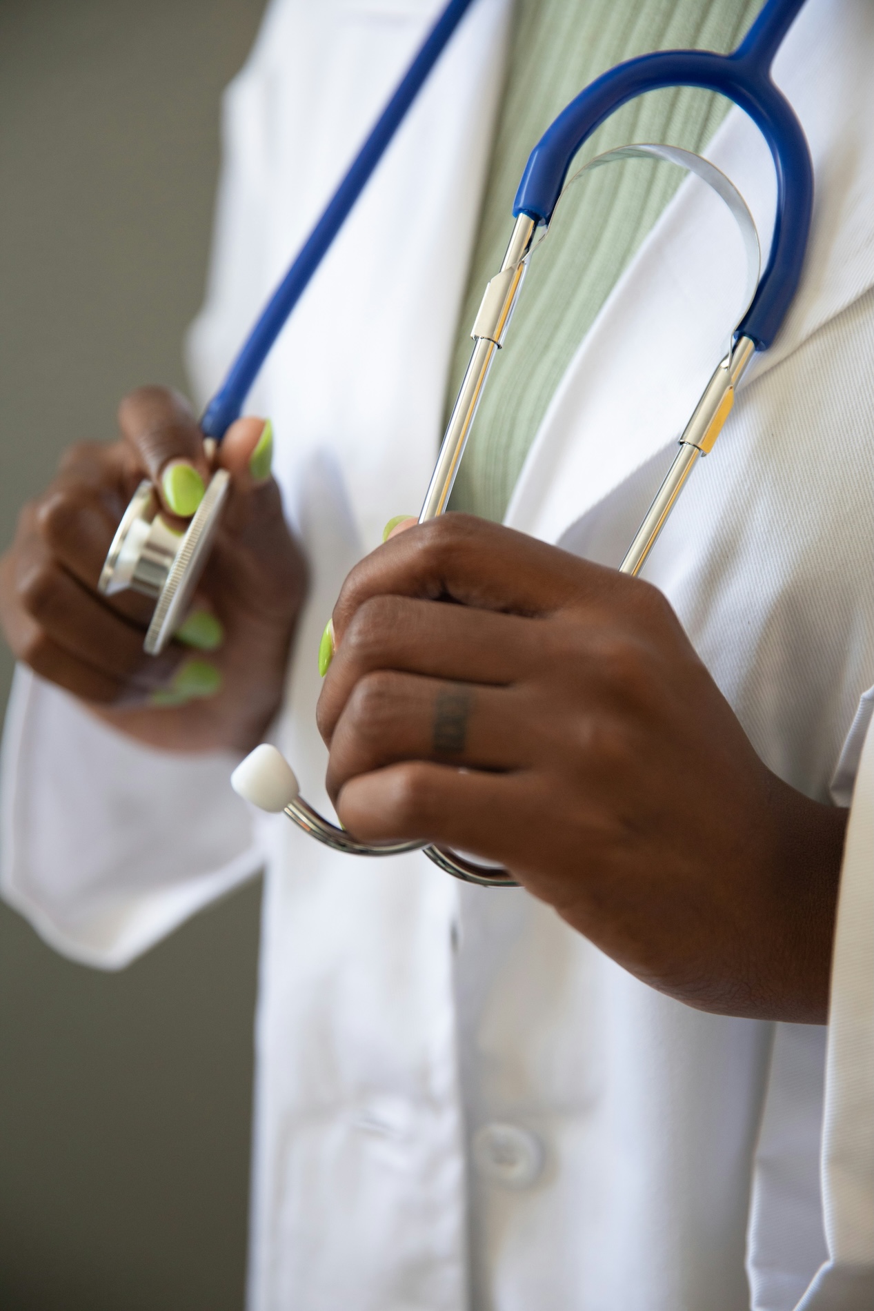 A male doctor holding a stethoscope in his hand. Only the stethoscope and his hand are visible, symbolizing medical expertise and professionalism.